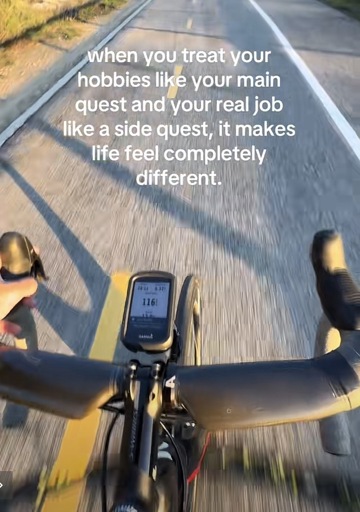 POV of a cyclist riding on a road with the caption “when you treat your hobbies like your main quest and your real job like a side quest, it makes life feel completely different.”